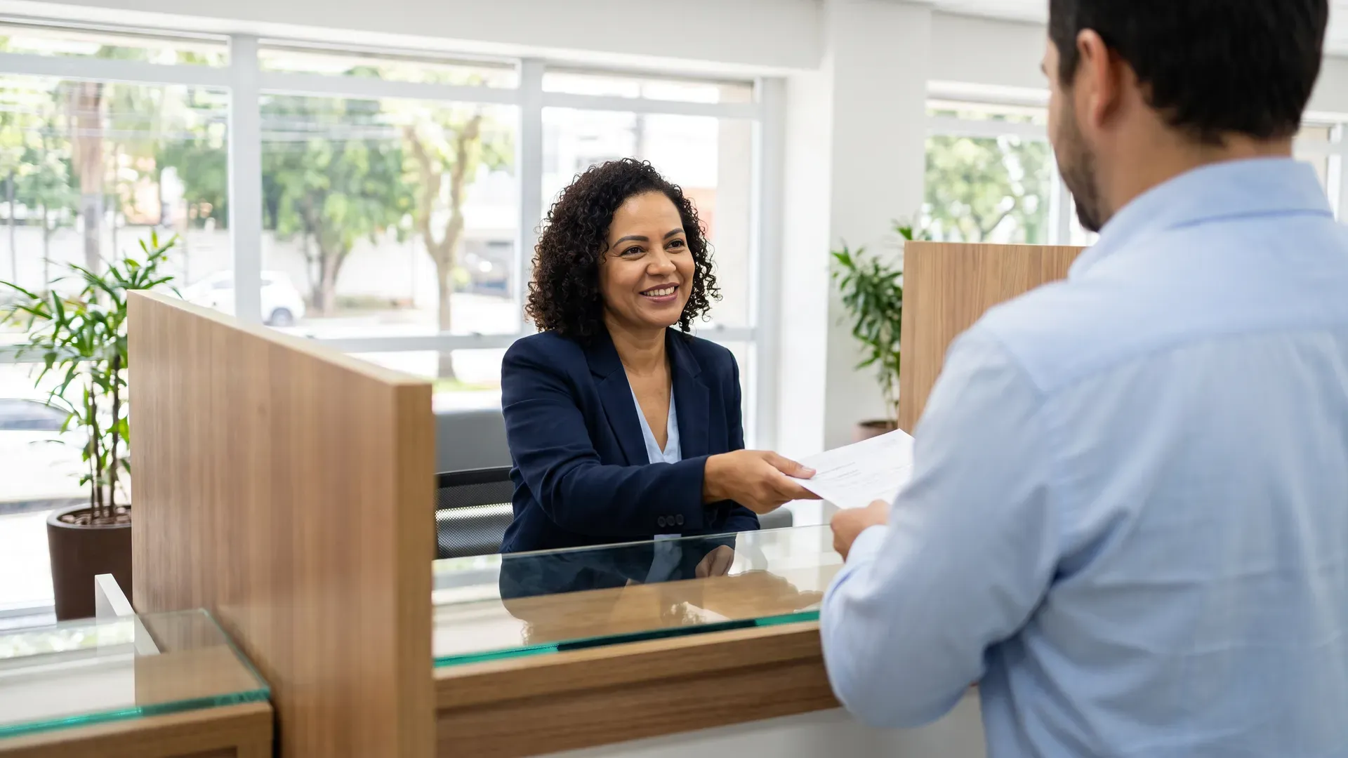 Atendente bancário auxiliando cliente no balcão de agência